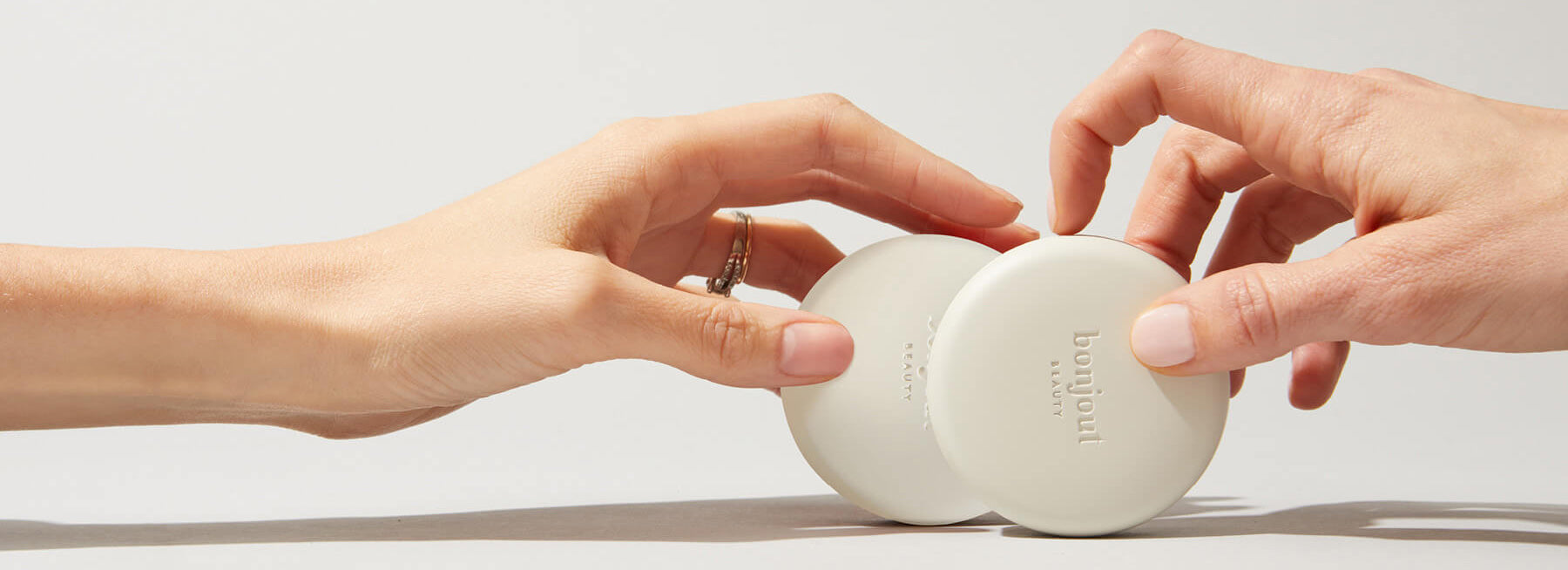 Two hands each holding Bonjout Beauty's Le Balm product