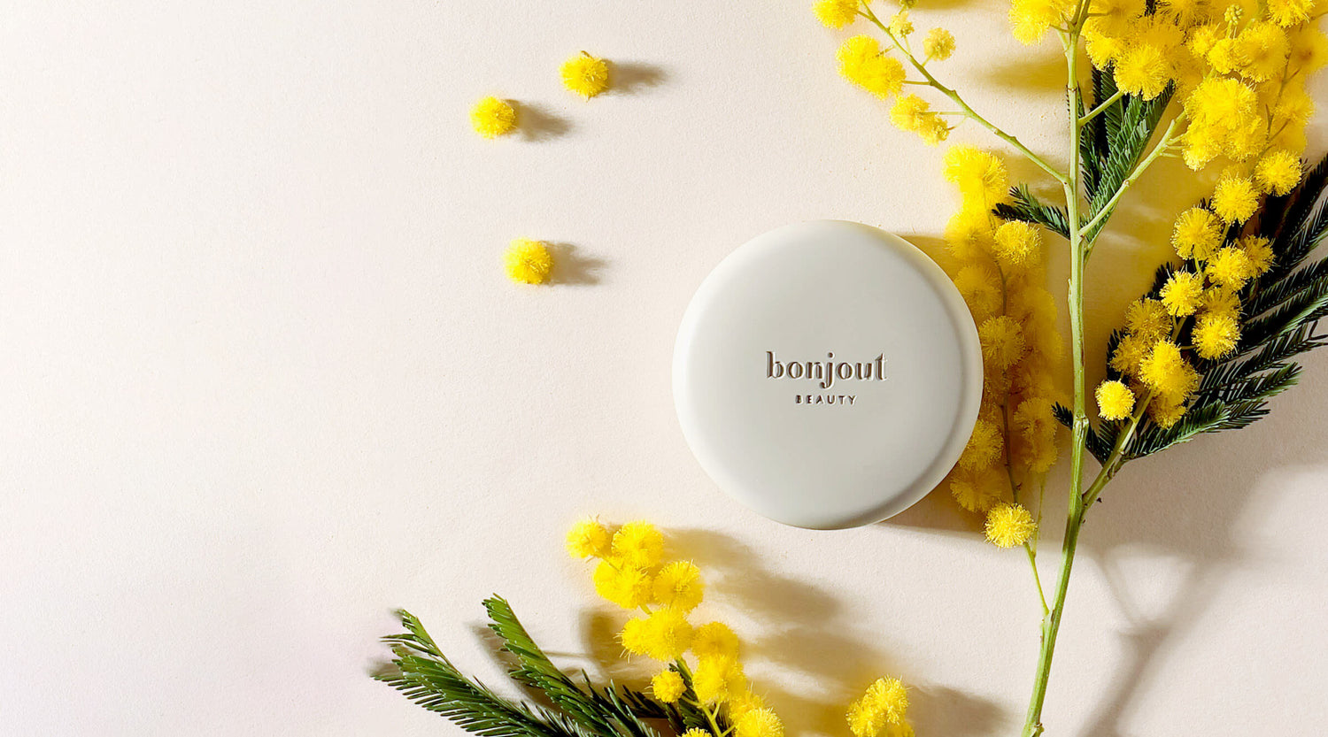 Bonjout Beauty's Le Balm product with yellow flowers on neutral background
