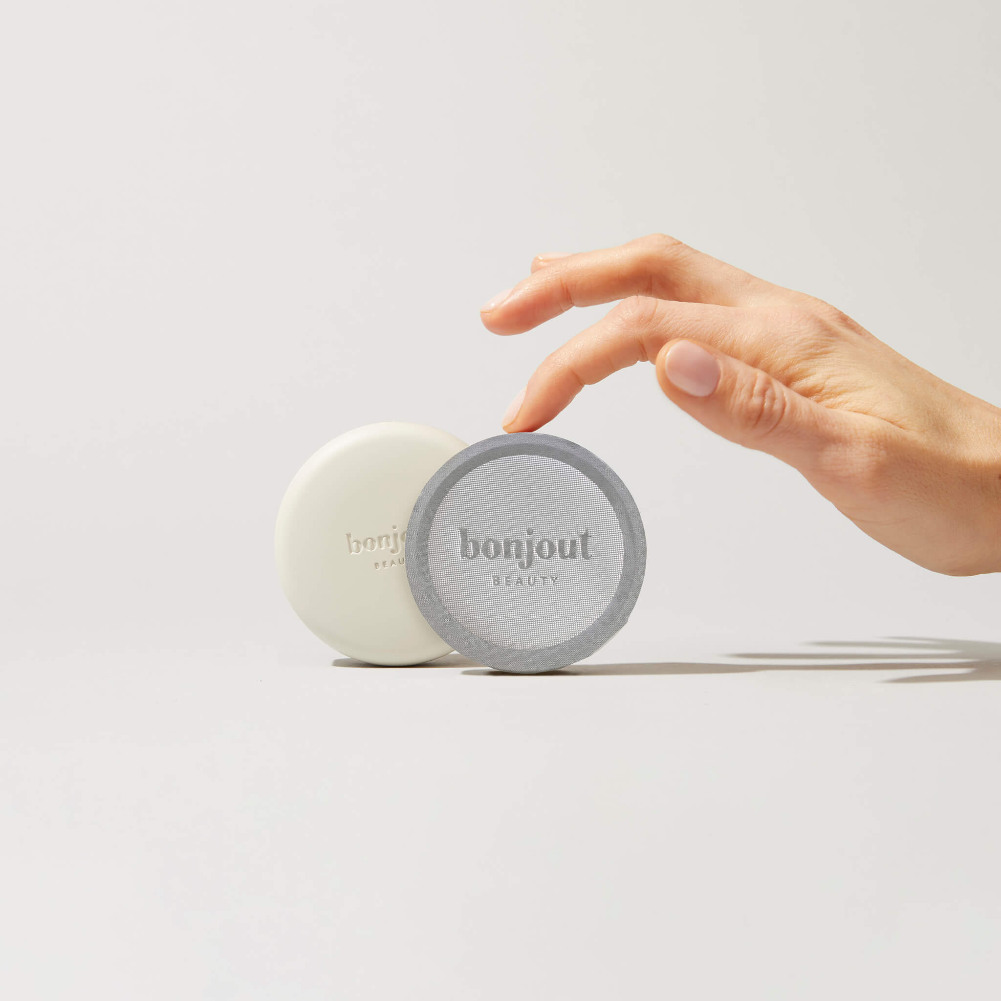 Woman&#39;s hand holding Bonjout Beauty&#39;s Le Balm product and refill tin