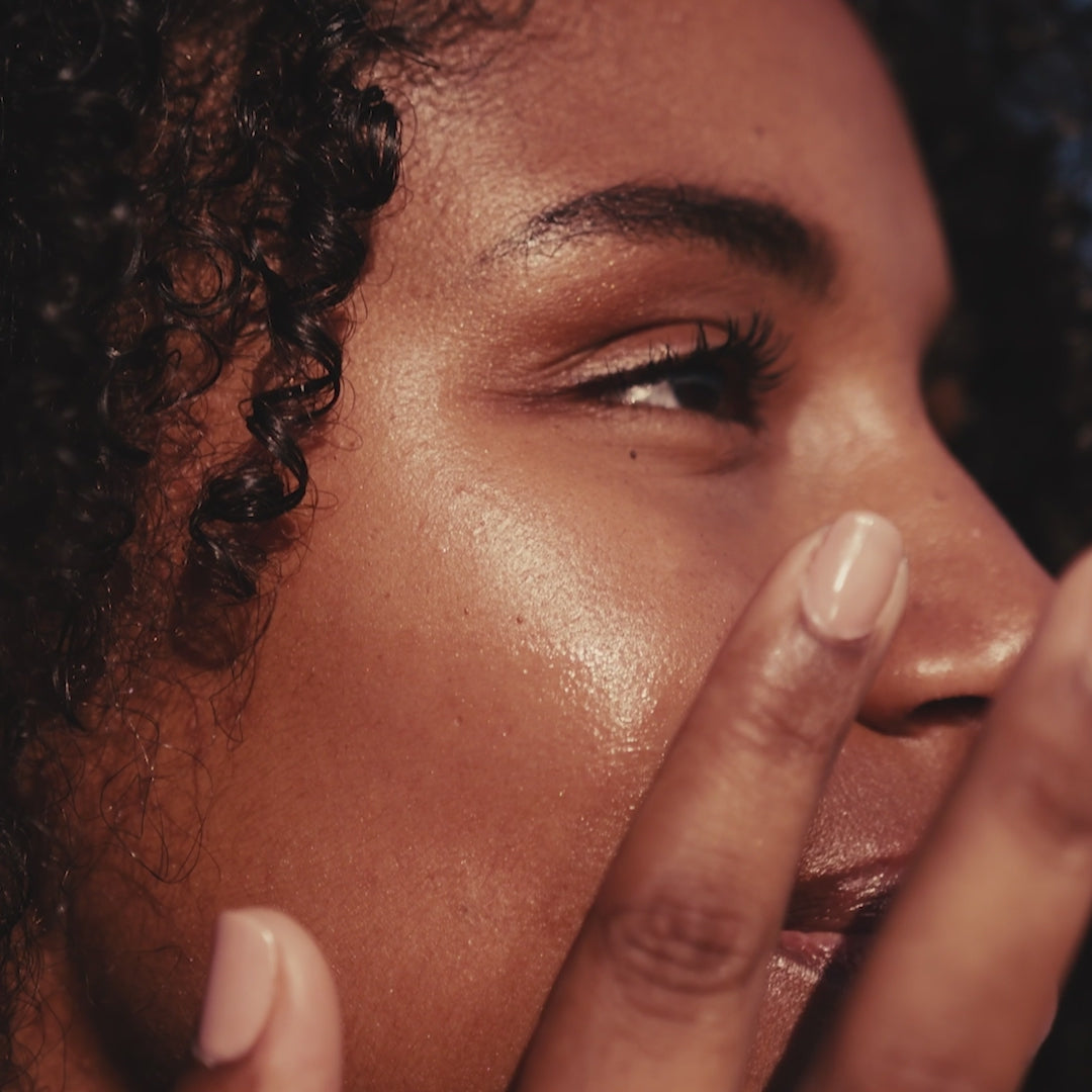 Woman touching her skin and smiling after applying Bonjout Beauty's Le Balm product